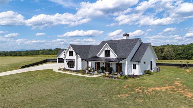 view of front of home with central AC unit, covered porch, and a front lawn