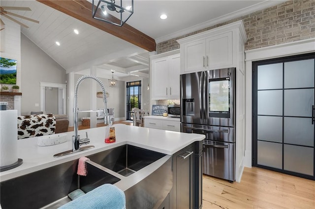 kitchen featuring sink, decorative light fixtures, stainless steel fridge, and white cabinets