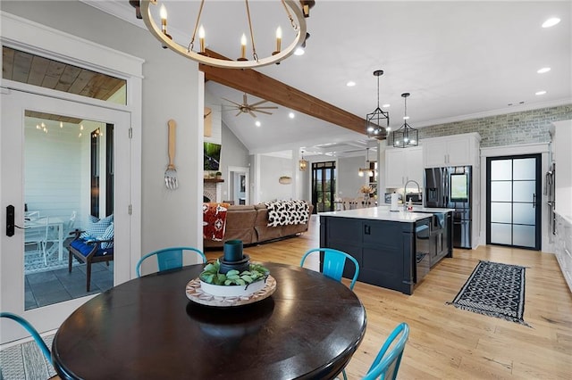 dining room with lofted ceiling with beams, ornamental molding, ceiling fan with notable chandelier, and light hardwood / wood-style flooring