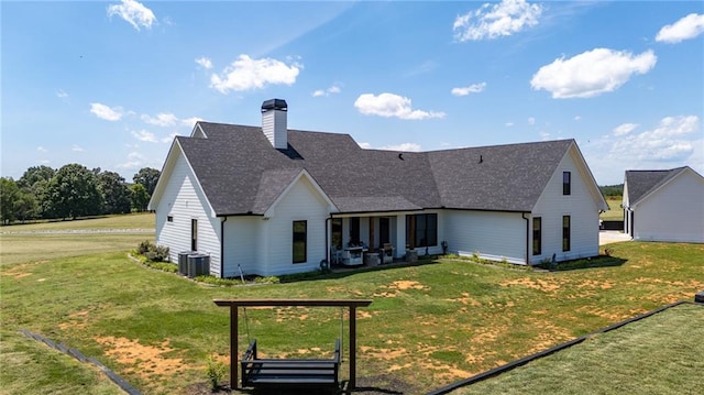 back of property with central AC unit and a yard