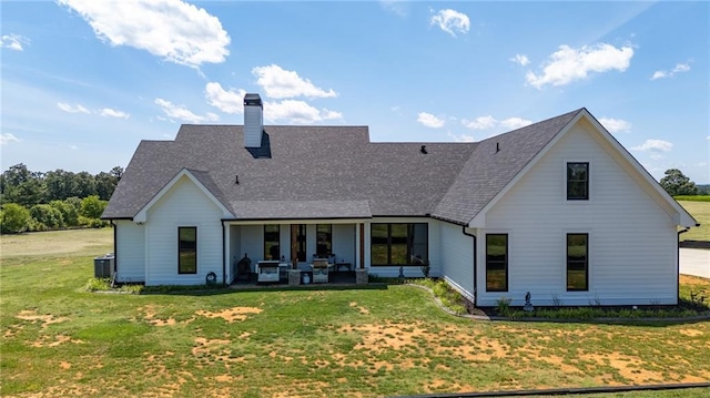 rear view of house with cooling unit, a yard, and a patio