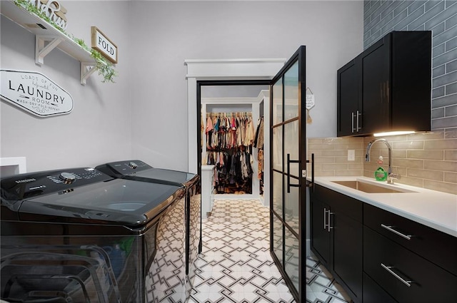 clothes washing area featuring washer and dryer, sink, and cabinets