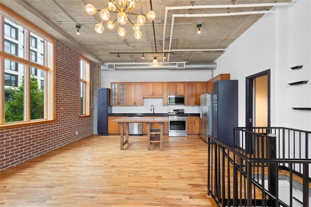 660 Glen Iris Drive # 206 & 109, Atlanta, GA 30308 - kitchen featuring stainless steel appliances, brick wall, light wood-type flooring, a high ceiling, and a chandelier