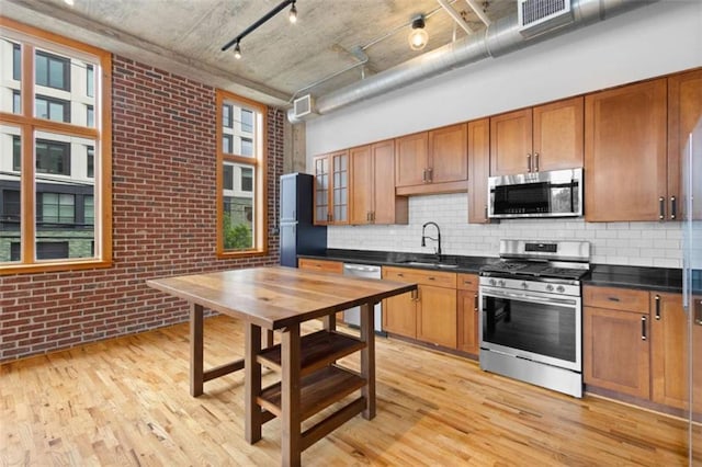660 Glen Iris Drive # 206 & 109, Atlanta, GA 30308 - kitchen featuring appliances with stainless steel finishes, light wood-style flooring, a sink, rail lighting, and brick wall