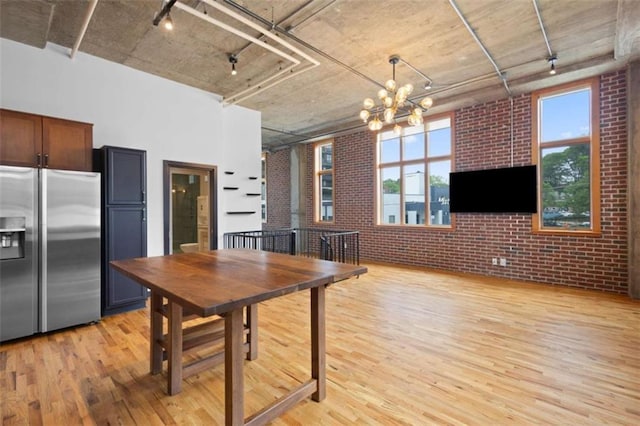660 Glen Iris Drive # 206 & 109, Atlanta, GA 30308 - dining room featuring brick wall, light wood finished floors, rail lighting, plenty of natural light, and a towering ceiling