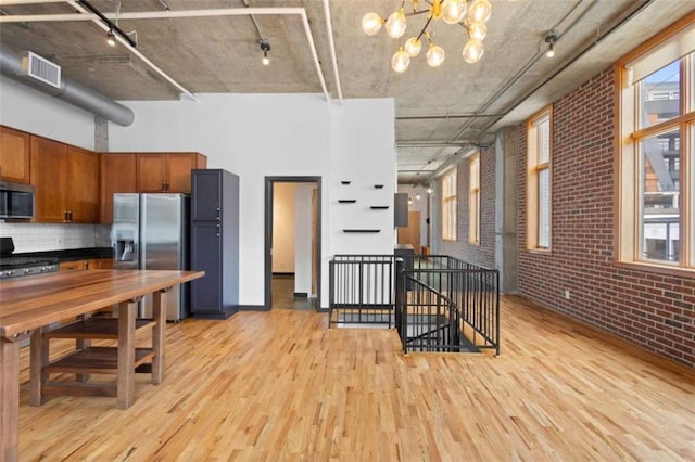 660 Glen Iris Drive # 206 & 109, Atlanta, GA 30308 - kitchen featuring stainless steel appliances, light wood-style floors, brick wall, track lighting, and a towering ceiling