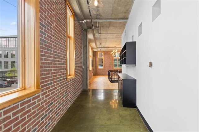660 Glen Iris Drive # 206 & 109, Atlanta, GA 30308 - hallway featuring finished concrete flooring, brick wall, a chandelier, and baseboards