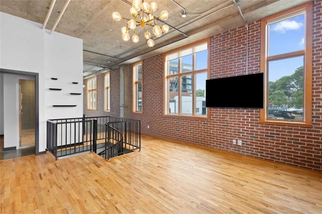 660 Glen Iris Drive # 206 & 109, Atlanta, GA 30308 - unfurnished living room with wood finished floors, brick wall, a chandelier, and healthy amount of natural light