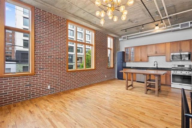 660 Glen Iris Drive # 206 & 109, Atlanta, GA 30308 - kitchen featuring stainless steel appliances, brick wall, light wood-style flooring, a sink, and a chandelier