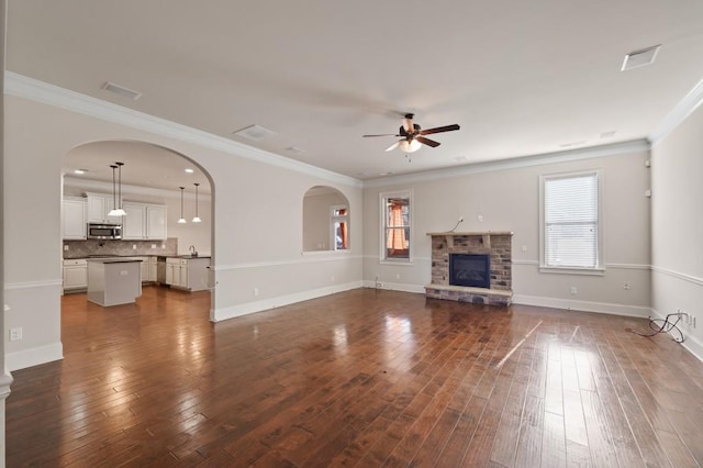 unfurnished living room with plenty of natural light, ceiling fan, a stone fireplace, and sink