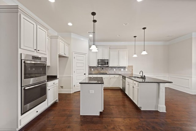 kitchen featuring white cabinets, sink, hanging light fixtures, appliances with stainless steel finishes, and kitchen peninsula