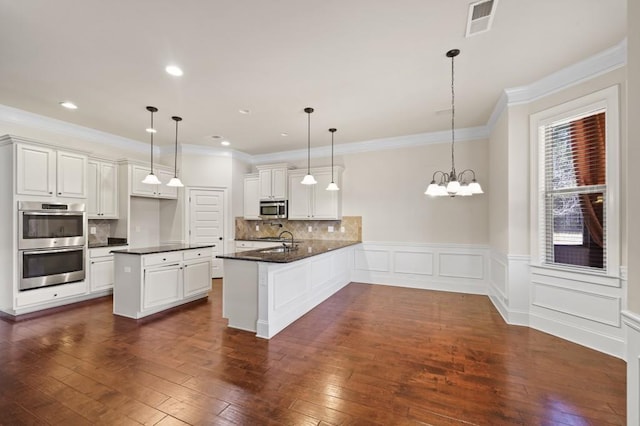 kitchen featuring kitchen peninsula, white cabinetry, stainless steel appliances, and decorative light fixtures