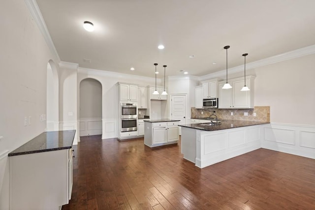 kitchen with sink, hanging light fixtures, a kitchen island, white cabinetry, and stainless steel appliances