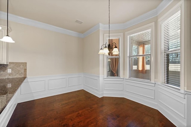 unfurnished dining area featuring crown molding, dark hardwood / wood-style flooring, and a chandelier