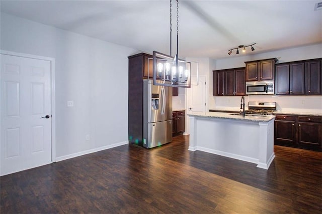 kitchen with dark wood-style flooring, decorative light fixtures, stainless steel appliances, dark brown cabinetry, and an island with sink