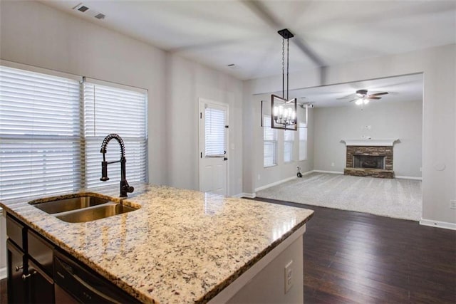 kitchen with visible vents, an island with sink, light stone counters, decorative light fixtures, and a sink