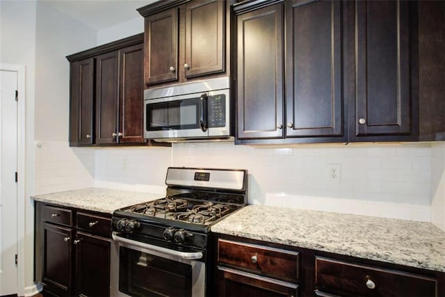 kitchen featuring appliances with stainless steel finishes, dark brown cabinetry, light stone counters, and tasteful backsplash