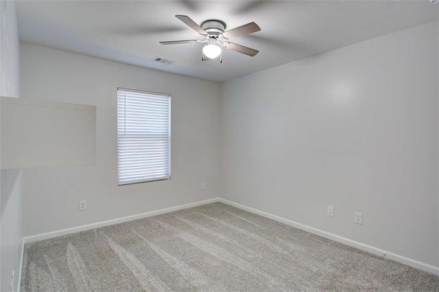 spare room featuring a ceiling fan, light colored carpet, visible vents, and baseboards