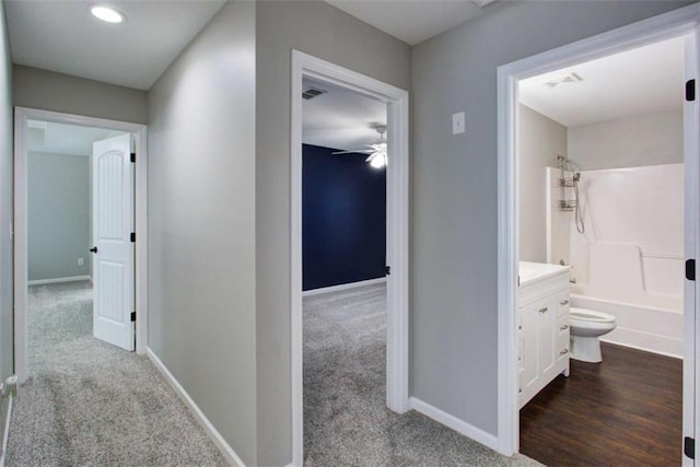 corridor featuring carpet floors, visible vents, and baseboards