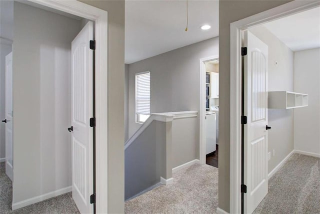 hallway with attic access, baseboards, light carpet, and an upstairs landing