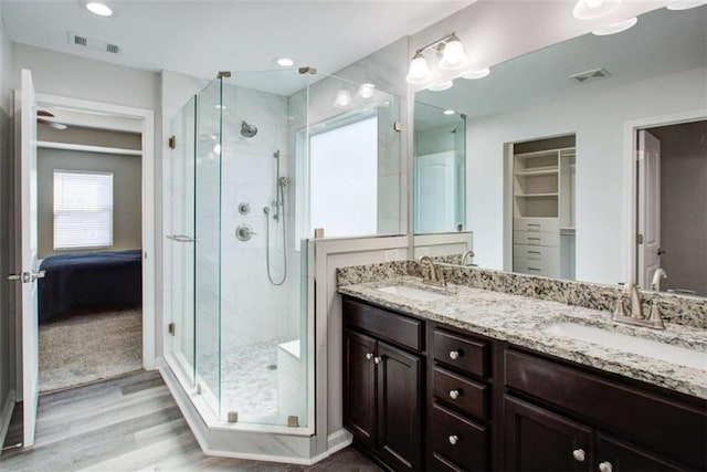 bathroom featuring a stall shower, visible vents, a sink, and wood finished floors