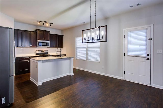 kitchen with pendant lighting, visible vents, appliances with stainless steel finishes, a kitchen island with sink, and a sink