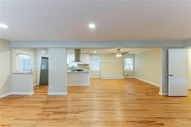 unfurnished living room featuring plenty of natural light, ceiling fan, and light wood-type flooring