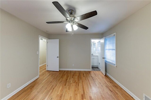 unfurnished bedroom with light hardwood / wood-style flooring, connected bathroom, and ceiling fan