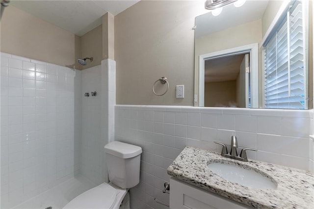 bathroom featuring vanity, toilet, tile walls, and tiled shower