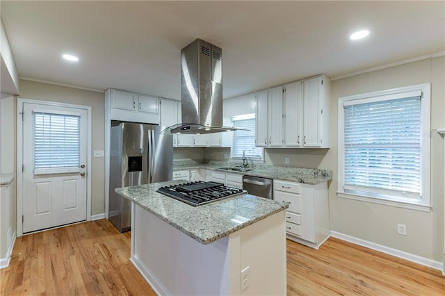 kitchen featuring light stone countertops, sink, island range hood, white cabinetry, and light hardwood / wood-style floors