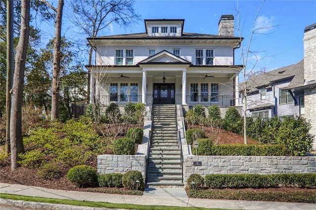 american foursquare style home featuring stairs, a chimney, a porch, and a ceiling fan