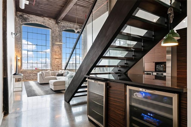 bar featuring wine cooler, a towering ceiling, wood ceiling, and beam ceiling