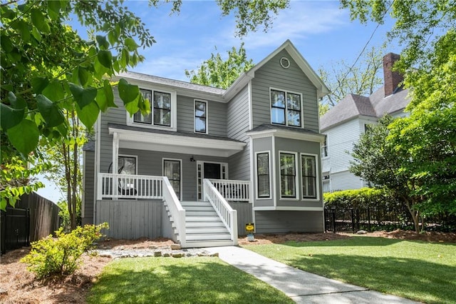 traditional-style house with fence, a porch, stairway, and a front yard