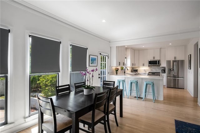 dining room with light wood finished floors, plenty of natural light, recessed lighting, and ornamental molding