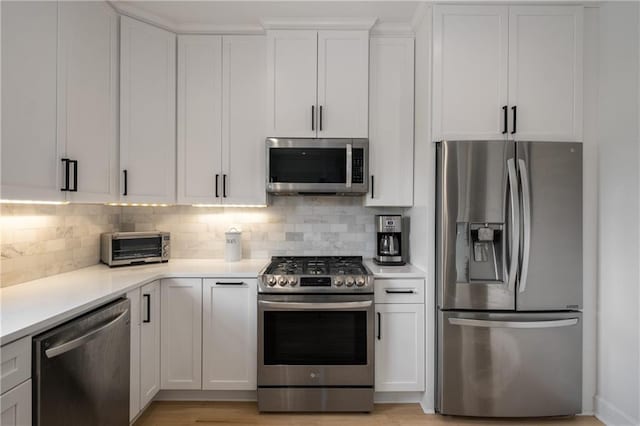 kitchen featuring white cabinets, stainless steel appliances, light countertops, and backsplash