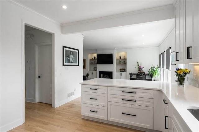 kitchen with a peninsula, light countertops, visible vents, and light wood finished floors