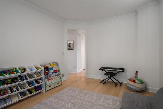 recreation room featuring baseboards, crown molding, and wood finished floors