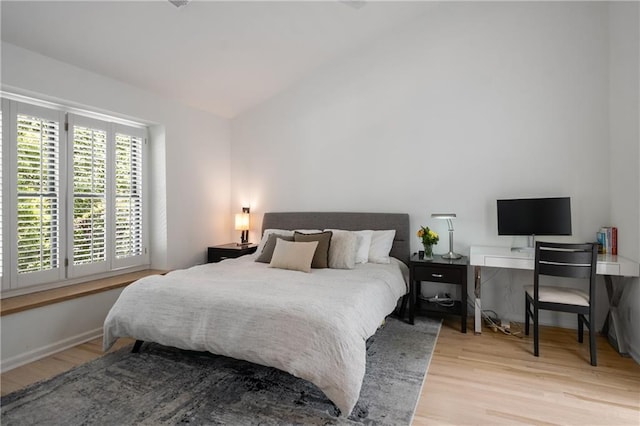 bedroom with lofted ceiling, baseboards, and wood finished floors