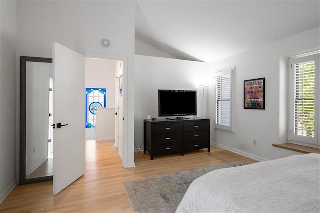 bedroom featuring vaulted ceiling, baseboards, and light wood-style flooring