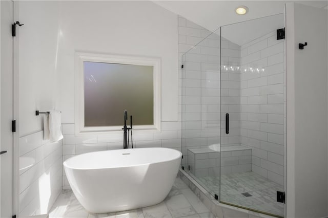 full bathroom featuring a shower stall, a freestanding tub, and marble finish floor