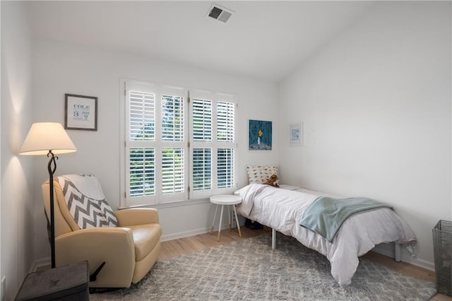 bedroom featuring lofted ceiling, visible vents, baseboards, and wood finished floors