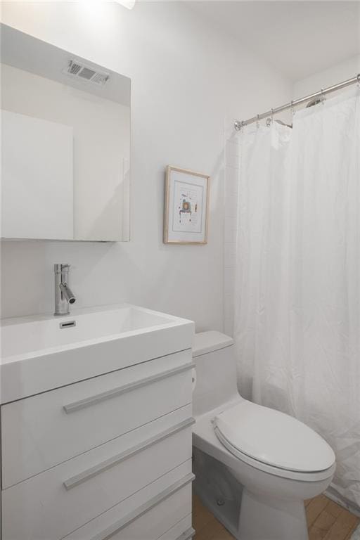 bathroom with wood finished floors, vanity, curtained shower, toilet, and visible vents