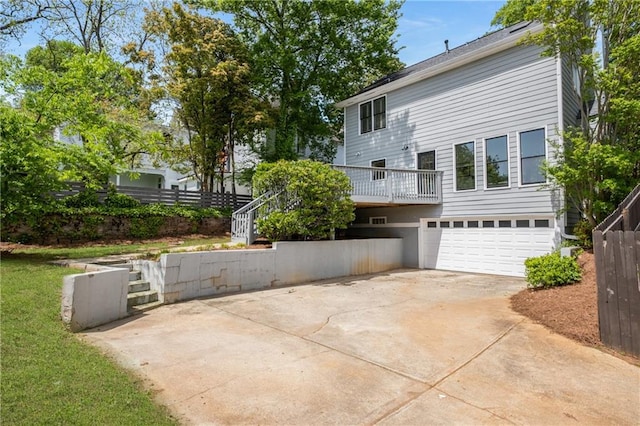 exterior space featuring an attached garage, driveway, fence, and stairway