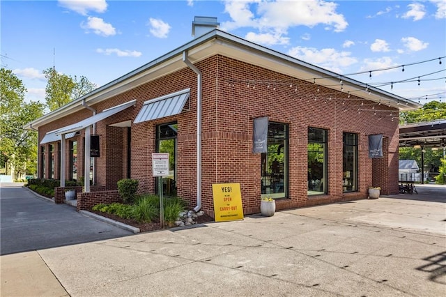view of property exterior featuring a chimney and brick siding