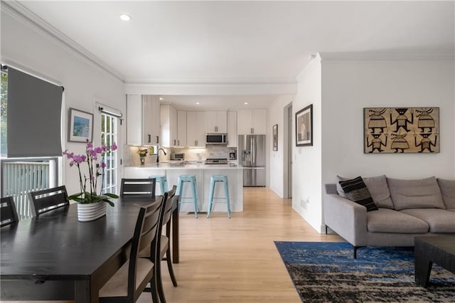 living area featuring recessed lighting, light wood-type flooring, a wealth of natural light, and crown molding