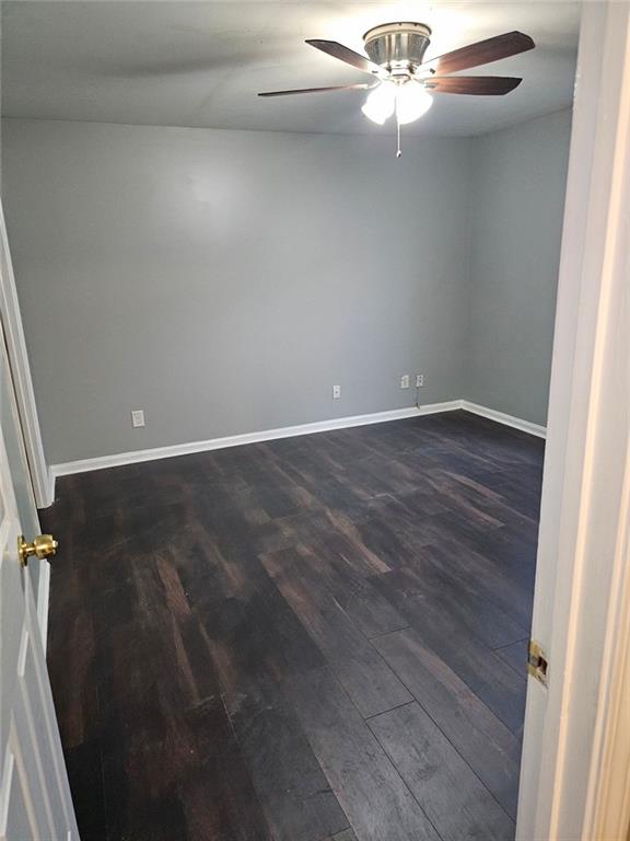 unfurnished room featuring dark wood-type flooring and ceiling fan