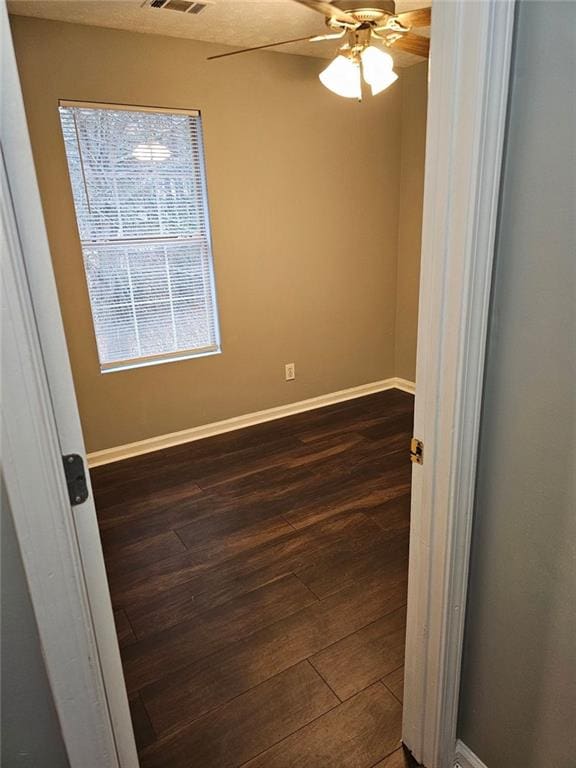 empty room with dark hardwood / wood-style flooring and ceiling fan