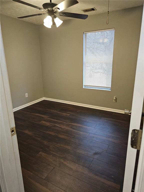 empty room featuring ceiling fan, dark hardwood / wood-style floors, and a textured ceiling