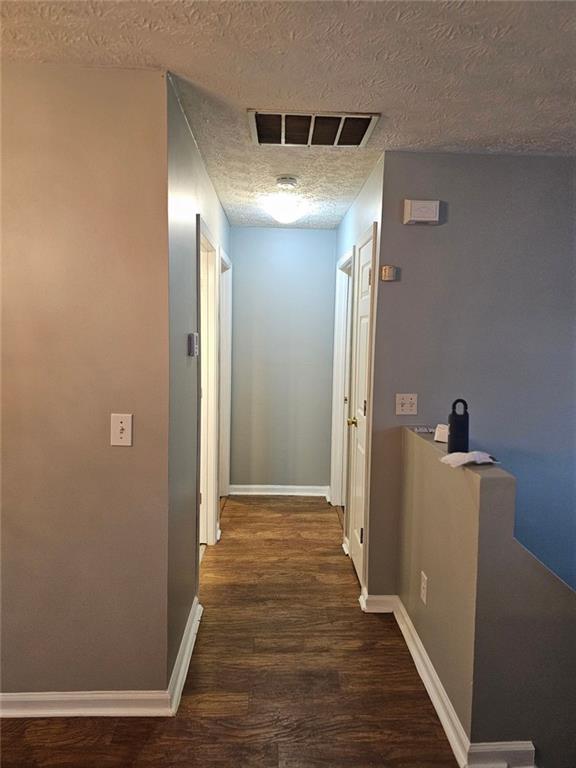 hall featuring dark hardwood / wood-style floors and a textured ceiling