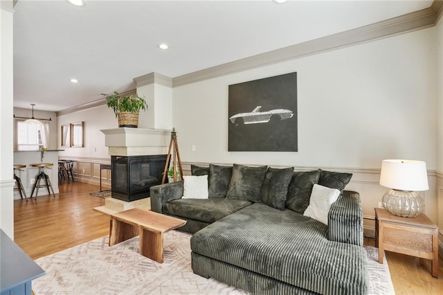 living room with ornamental molding, a wainscoted wall, and wood finished floors